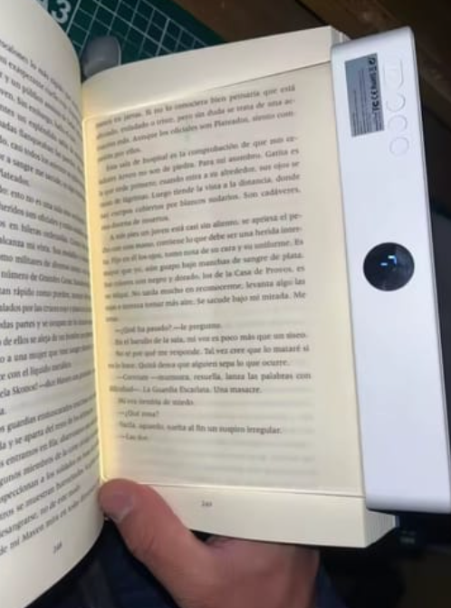 Hand holding a reading screen over an open book
